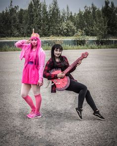 two women in costumes are posing with guitars