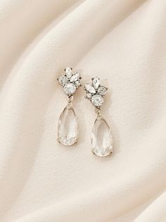 a pair of earrings on top of a white cloth