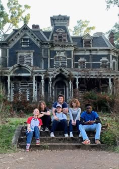 a group of people sitting on steps in front of an old house