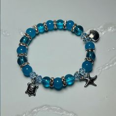 Dive into summer with our Unique Blue Summer Beach Themed Charm Bracelet! This stunning piece, featuring blue glass beads, measures approximately 7 inches and is designed to capture the essence of beach days and ocean waves. Whether you're lounging by the shore or enjoying a casual day out, this charm bracelet is the perfect accessory. It's an ideal gift for moms, friends, or any woman who loves unique and handmade jewelry. Perfect for stacking, this boho-chic, crystal-adorned bracelet adds a to Blue Bracelets, Ocean Bracelet, Pony Bead Bracelets, Pink Beaded Bracelets, Beachy Jewelry, Beads Candy, Blue Beaded Bracelets, Gems Bracelet, Beaded Necklace Diy