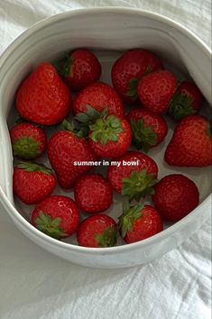 some strawberries are in a white bowl on a bed with the words summer in my bowl