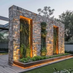 an outdoor living area with stone walls and plants growing on the wall, surrounded by grass