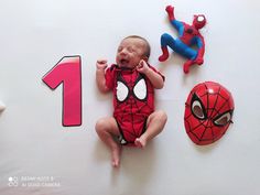 a baby is laying on the floor next to some spider - man masks and toys