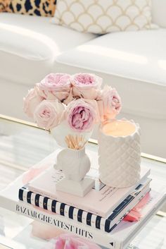 a table topped with books and vases filled with flowers on top of each other