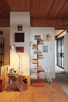 a room with a wooden floor and bookshelf next to a wall filled with pictures