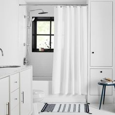 a white bathroom with black and white decor on the shower curtain, rug, sink and toilet