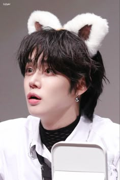 a man with black hair wearing a white shirt and bunny ears