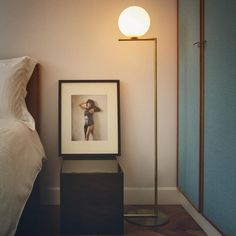 a lamp is next to a bed with a picture on it and a framed photo