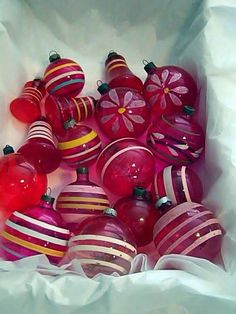 a bunch of red and pink ornaments in a white bag