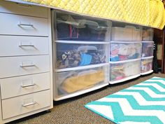 an organized bedroom with drawers and storage bins on the bottom shelf next to a bed