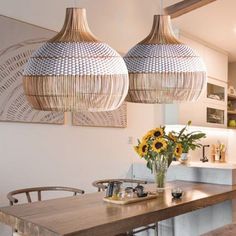 two lamps hanging over a wooden table with flowers in vases on the top and bottom