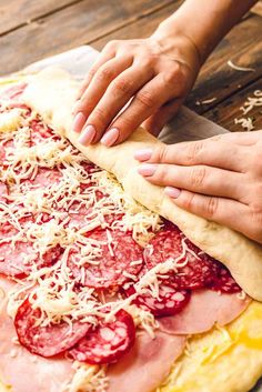 someone is making a pizza with pepperoni, cheese and ham on the dough sheet