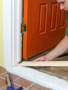 a man working on a door frame in front of a red door