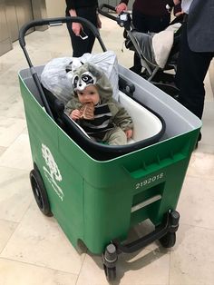 a baby dressed as a panda in a shopping cart at an airport with other people