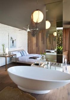 a large white bath tub sitting inside of a bathroom next to a bed and desk