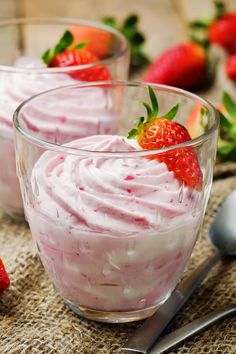 two small bowls filled with whipped cream and strawberries on top of burlly cloth