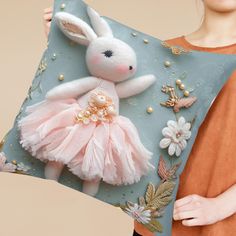 a woman holding a pillow with a stuffed animal on it