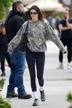 a woman in black leggings walking down the street with a man behind her