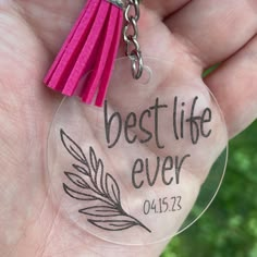 a person holding a clear keychain with the words best life ever on it