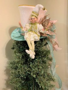 a doll is sitting on top of a christmas tree ornament that has been made to look like an elf