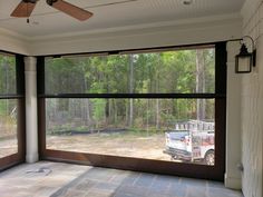 an empty room with large windows and a truck in the back ground, looking out onto a wooded area