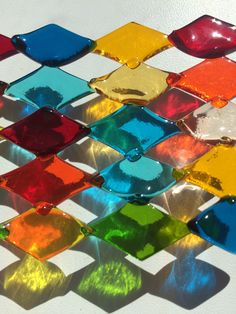 colorful glass tiles are arranged on a white surface with light reflecting off them in the background