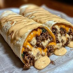 two burritos covered in cheese and ground beef