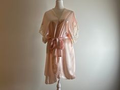 Vintage Val Mode Lingerie pink belted robe with floral and lace detail on sleeves.  The robe body is semi sheer.  100% polyester.  Made in the U.S.A.  Please note this is a vintage item and does show signs of ware such as pilling of fabric and small snags.  Most notable is a snag on the back (see photo).  In overall good vintage condition with no rips, stains, holes, or tears. Labeled size large but fits best as modern small to medium.  Displayed on size 6 mannequin.   Approximate measurements: 37" top to bottom 38" wide (adjustable) Lingerie Rosa, Lingerie Pink, Belted Robe, Bridal Party Robes, Rose Vintage, Semi Transparent, Mode Vintage, Bridesmaids Gifts, Lace Detail