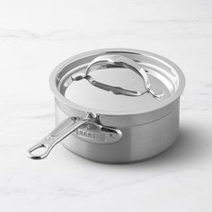 a stainless steel pot with lid on a white marble countertop, showing the handle