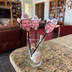 three cowboy hats are sticking out of the top of a glass on a table in a living room