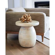 a white table with a pine cone on it in front of a couch and fireplace