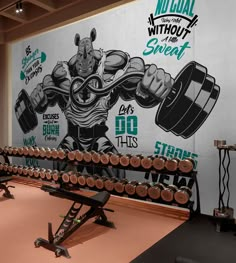 a gym with two rows of dumbs in front of a large mural on the wall