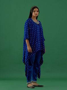 One of our timeless classics, hand-stitched exclusively for your bespoke taste. Channel your desi diva vibes and experience luxury in our all-time favourite festive collection. Royal Blue Bandhani Modal Satin Asymmetric Tunic featuring all-over bandhani work, a round neck, quarter sleeves, and embellished shoulders with ghungroos. Fabric: Modal Satin Color: Royal blue Note: Bottoms shown in the image not included with the tunic. Bottom can be bought separately Available in other colors The produ Indigo Traditional Designer Kurta, Traditional Indigo Kurta For Designer Wear, Designer Bandhani Print Kurta With Traditional Drape, Designer Wear Kurta With Bandhani Print And Traditional Drape, Indigo Bollywood Traditional Wear, Bollywood Style Designer Traditional Wear In Indigo, Festive Designer Indigo Kurta, Bollywood Style Bandhani Print Kaftan For Festive Occasions, Bollywood Style Indigo Straight Kurta