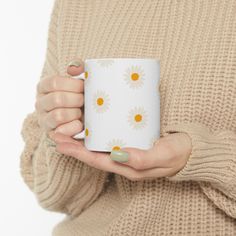 a woman is holding a coffee mug with daisies on the outside and yellow dots on the inside