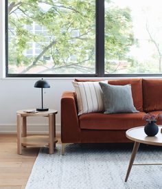 a living room with a couch, table and large window overlooking the trees in the background