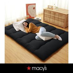 a woman laying on top of a black mattress