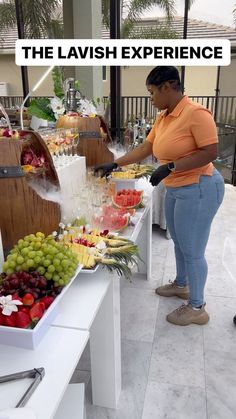 a woman standing in front of a table filled with fruit