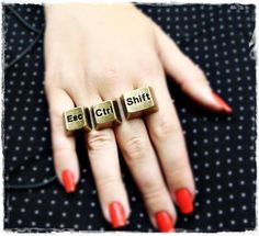 a woman's hand with red nail polish and two wooden letters that spell out each word