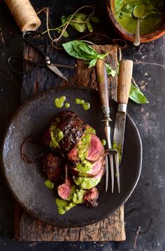 a plate with some meat and green sauce on it