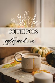 a coffee mug sitting on top of an open book next to candles and pumpkins