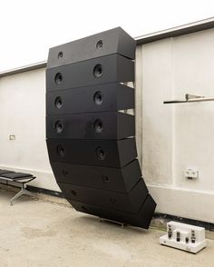 a large black sculpture sitting on top of a cement floor next to a white wall