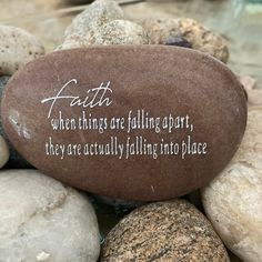 a rock with the words faith written on it surrounded by rocks and pebbles in water