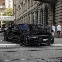 a black car is parked on the side of the road in front of some buildings