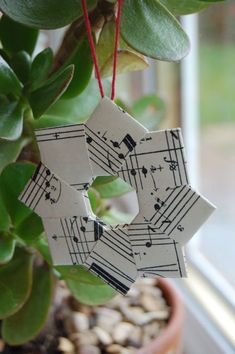 an ornament made out of sheet music is hanging from a plant in front of a window