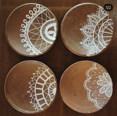 four wooden plates with white designs on them