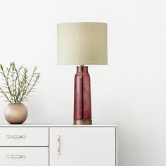 a red lamp sitting on top of a white dresser