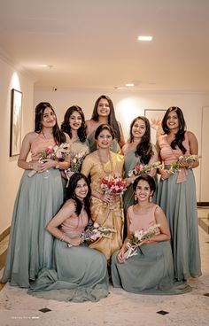 a group of women standing next to each other wearing dresses and holding bouquets in their hands