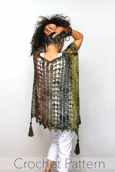 a woman in white pants and a green shawl is posing with her hands on her head