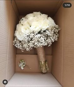 a bouquet of white roses and baby's breath in a cardboard box