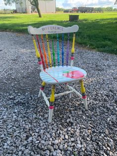 a colorful wooden chair sitting on top of gravel